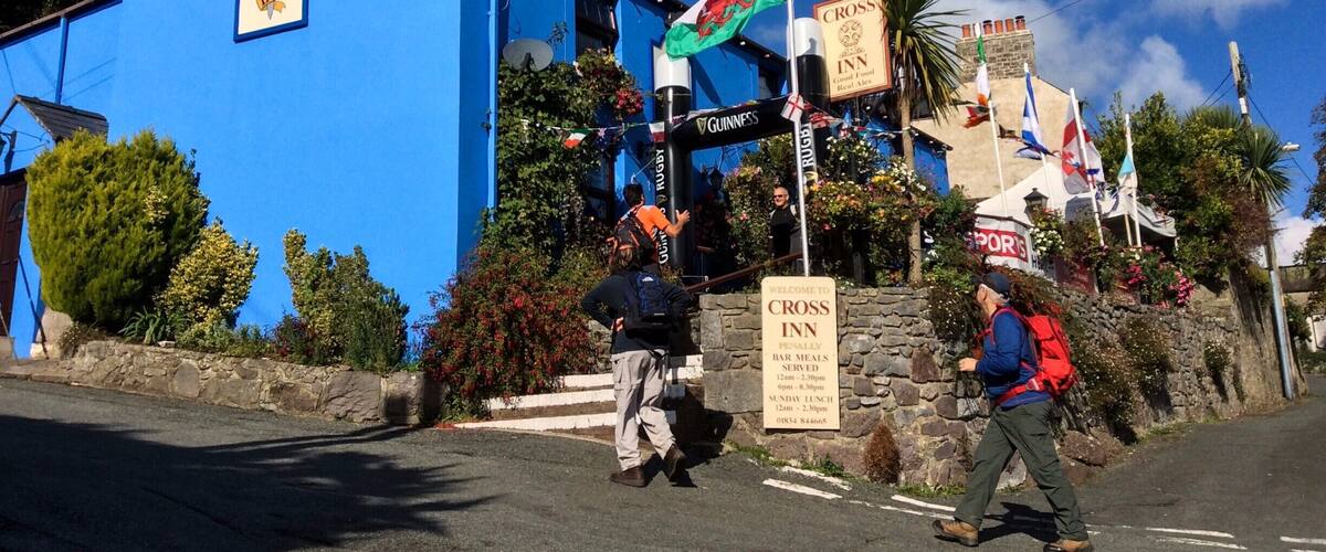 A blue building with flags and signs for Cross Inn, Guinness, and other brands.