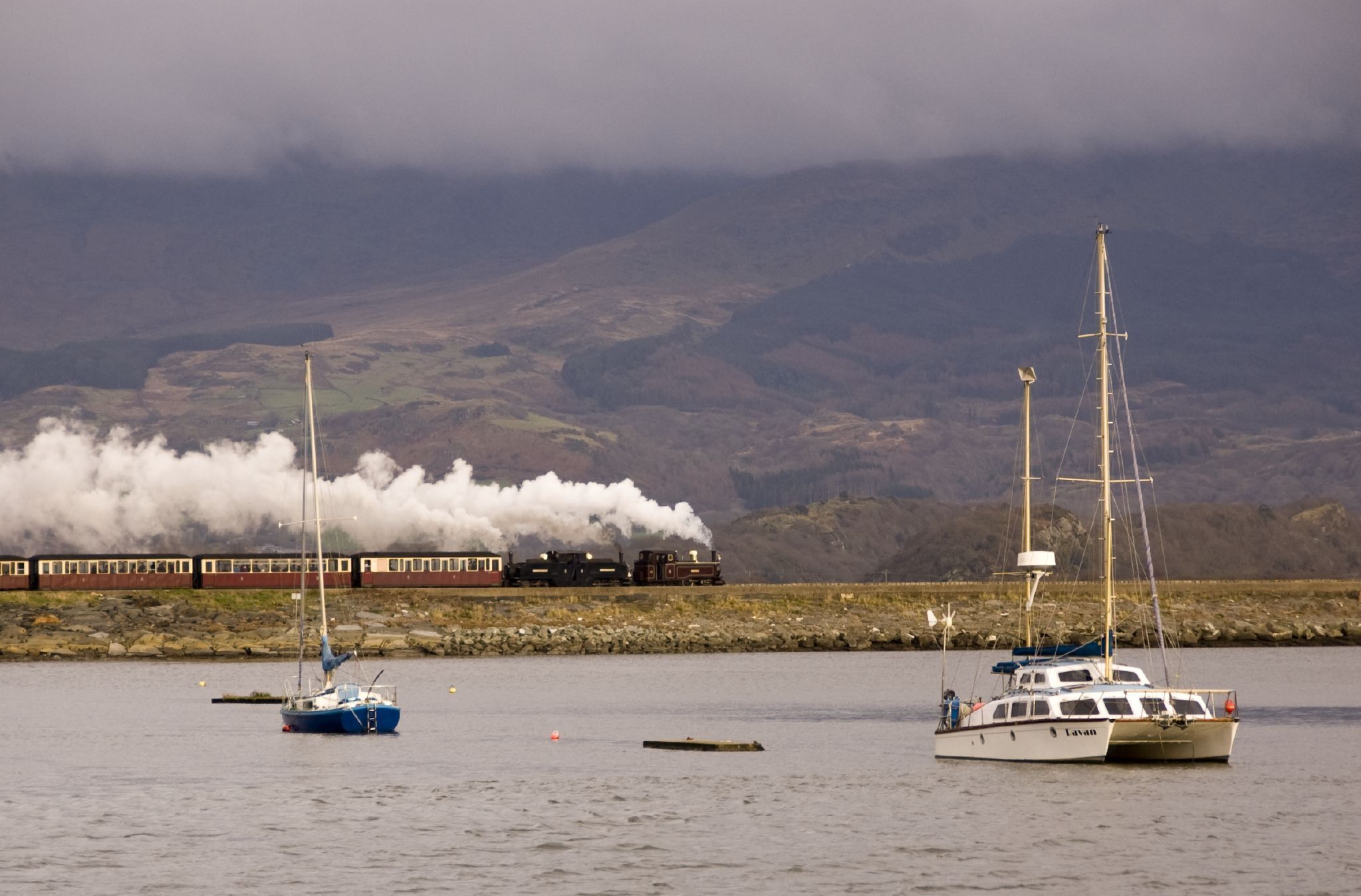 A Ffestiniog Railway train hauled by Earl of Merioneth and Taliesin heads across the Cob on its way to Blaenau Ffestiniog.