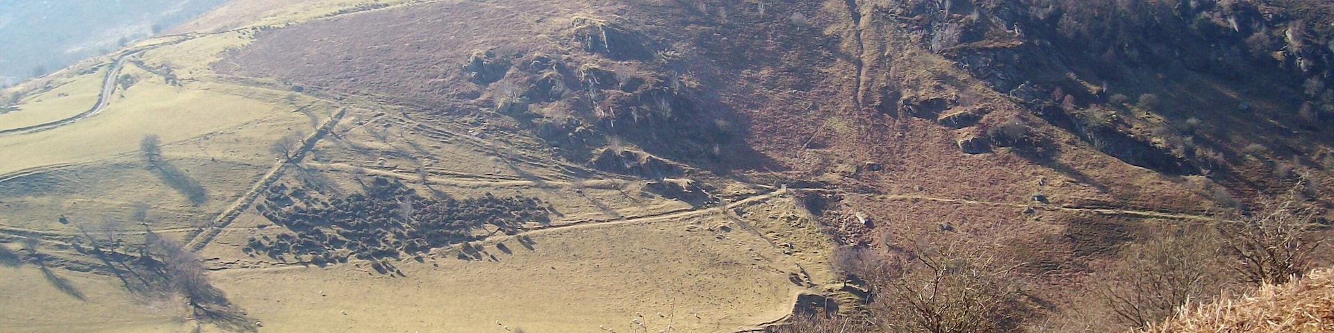 A mountainous landscape with a prominent peak, a valley, and a winding road.
