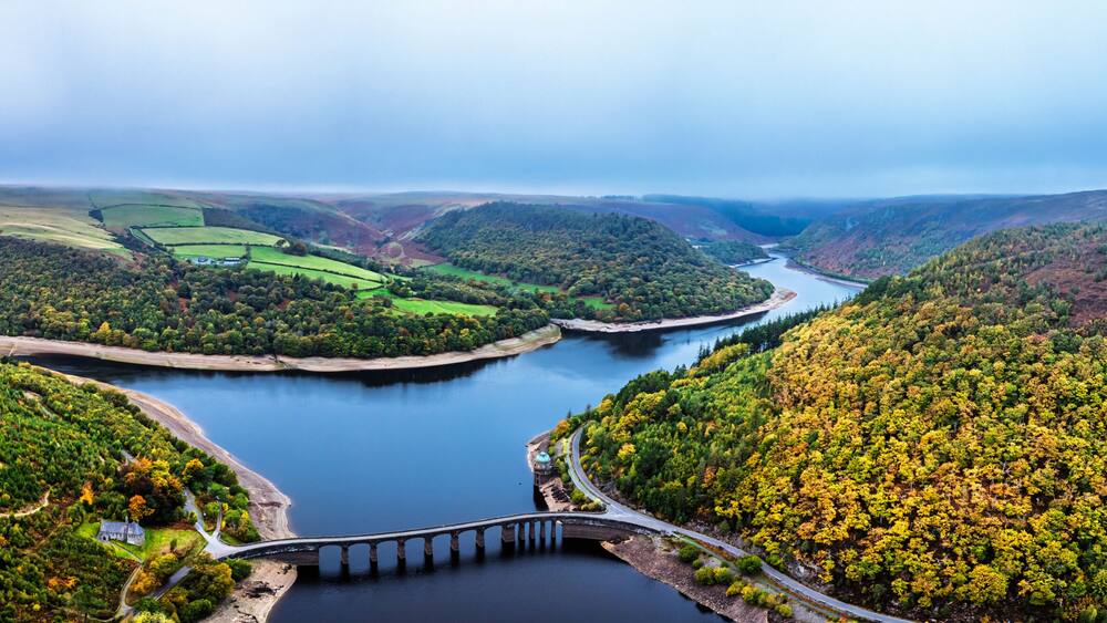 A river meandering through a valley with terraced fields and a bridge.