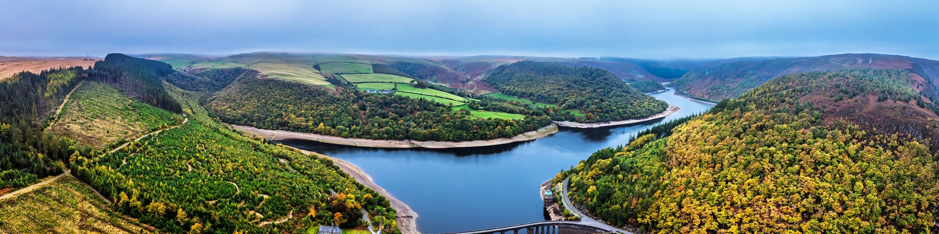 A river meandering through a valley with terraced fields and a bridge.
