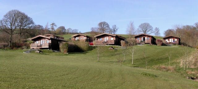 Oak Wood Lodges This picture straddles two squares. The closest lodge (on the left), the grass slope in the foreground and the camera position are all in this square. The further lodges are in SN9970. There are 11 lodges in all, offering spectacular views across the Elan Valley. For further information, visit http://www.oakwoodlodges.co.uk/.