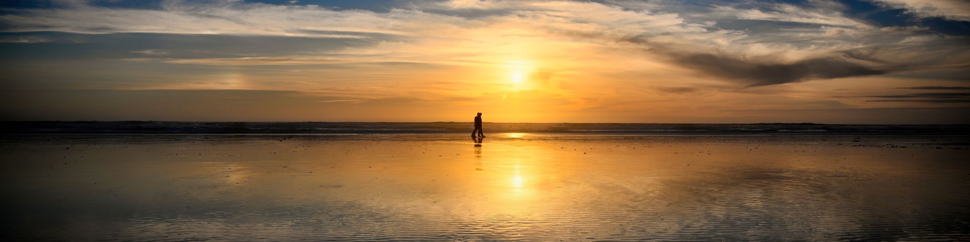 Couple walking on Freshwater West beach at sunset in Pembrokeshire, Wales