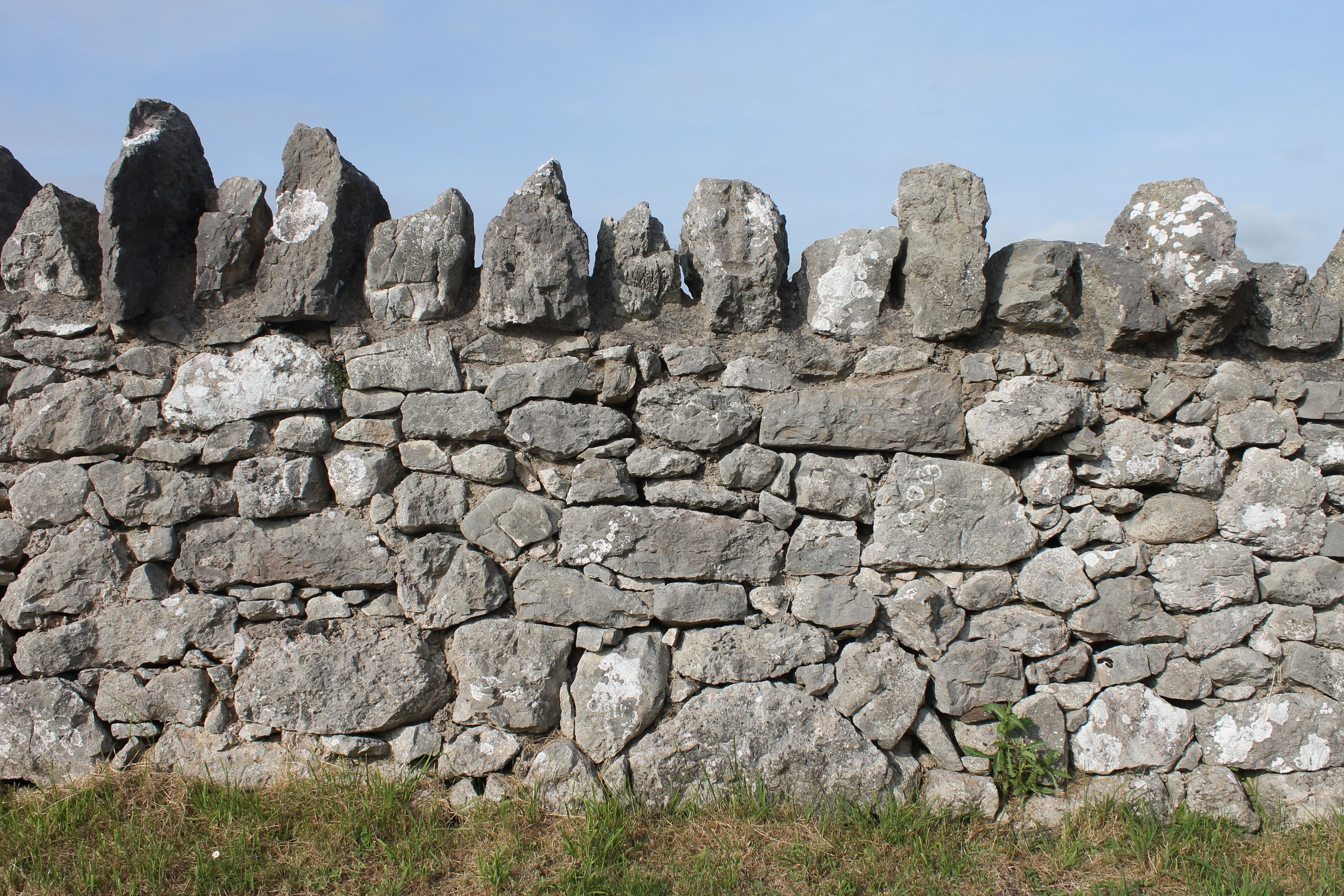 Un muro de piedra con piedras de formas irregulares y manchas de liquen.