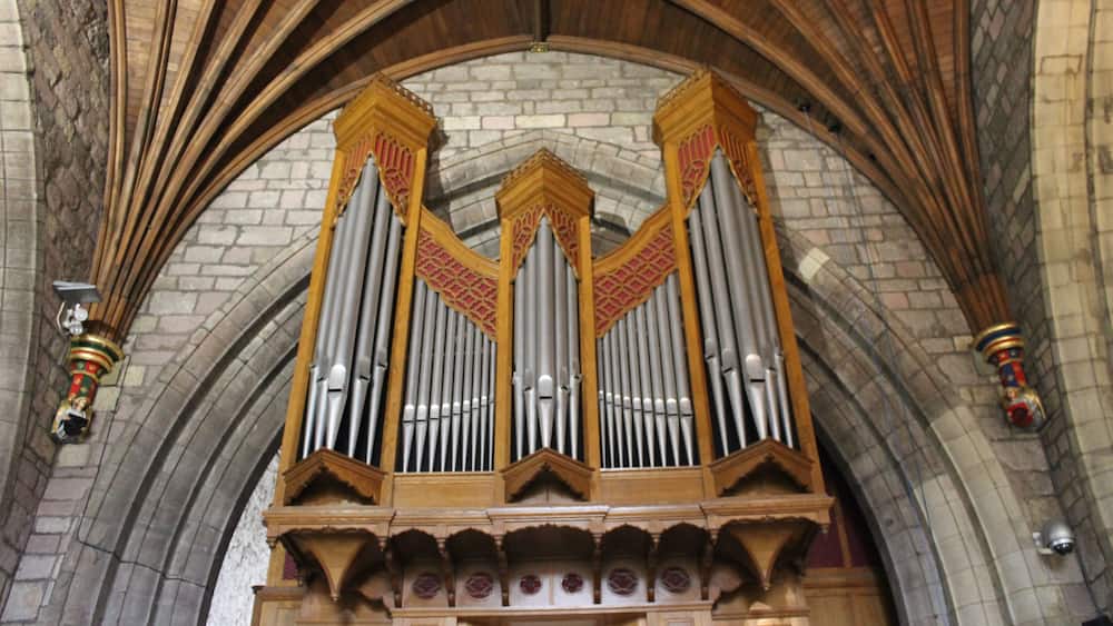 A large pipe organ with intricate carvings and a stone arch ceiling.