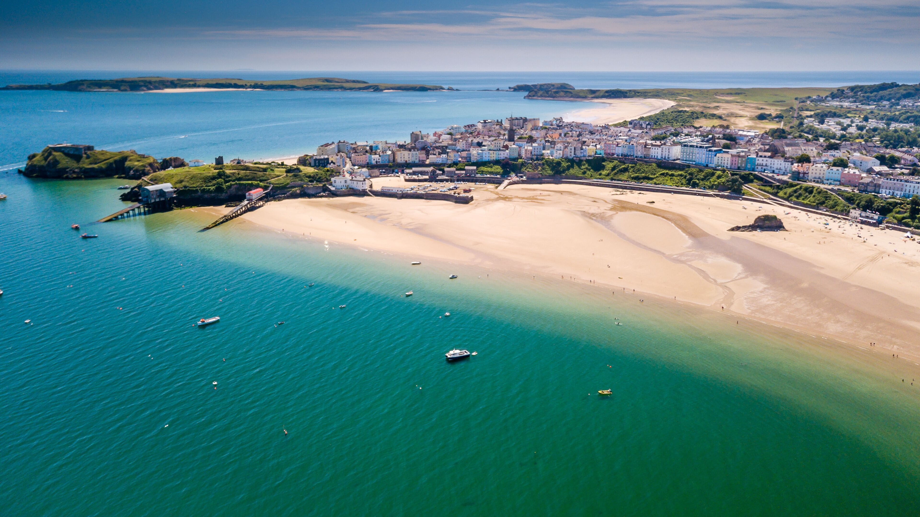 Un pueblo costero con una playa de arena, un muelle y un mar azul cristalino.