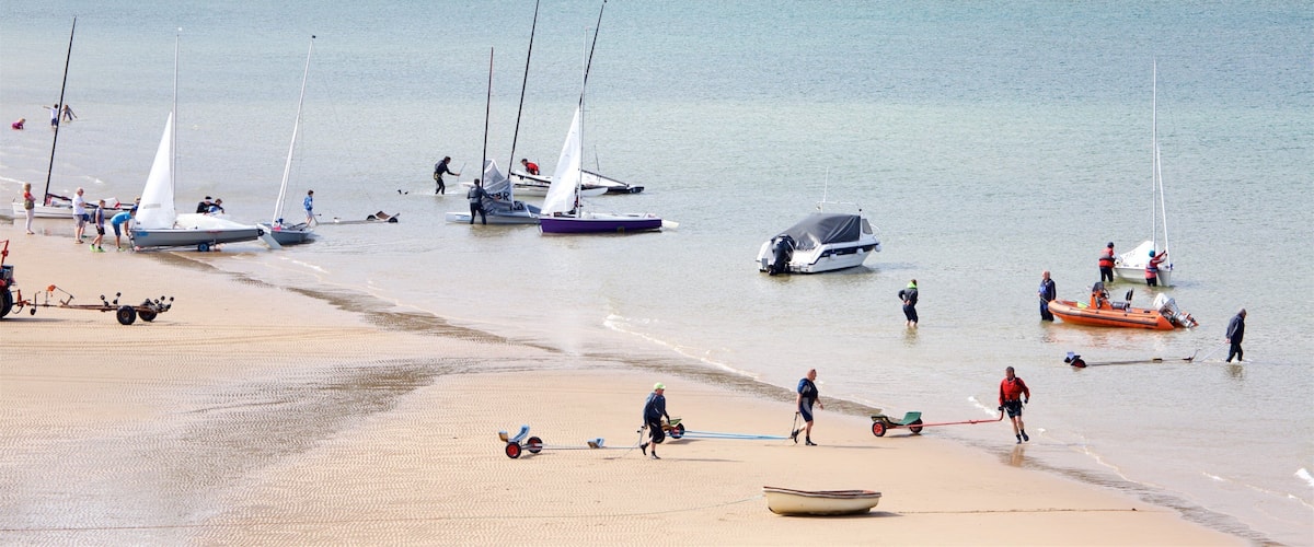 A sandy beach with several sailboats anchored near the shore.