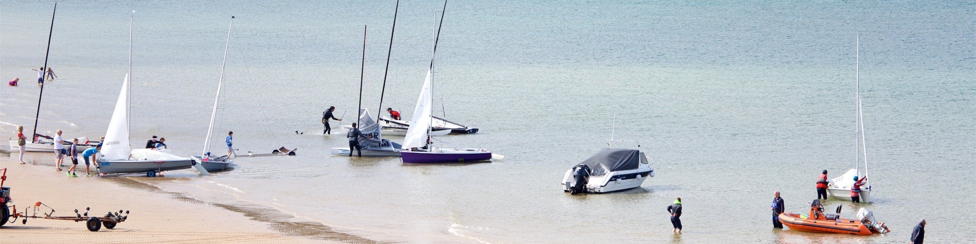 A sandy beach with several sailboats anchored near the shore.