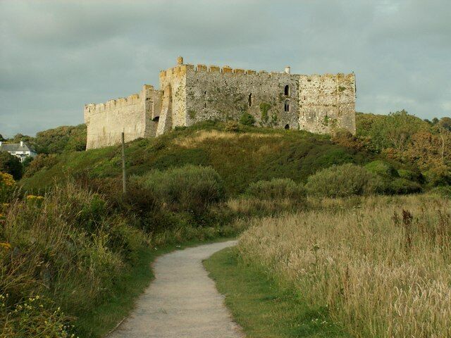 A medieval castle on a hill with a dirt path leading to it.