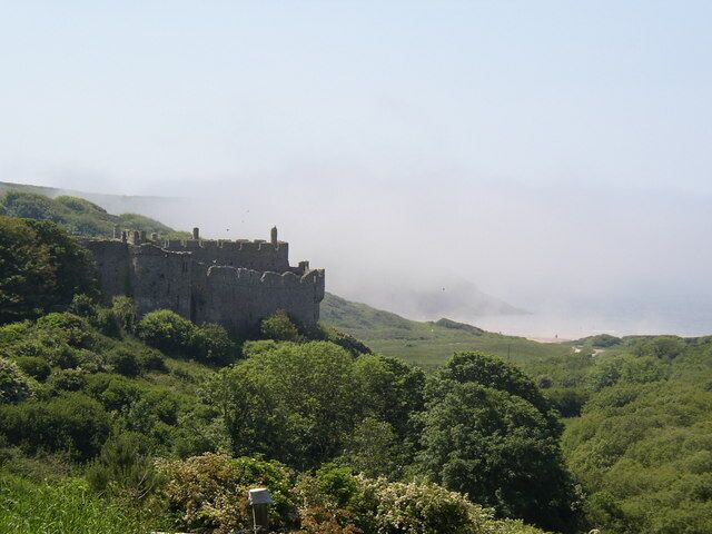 A medieval castle on a hill surrounded by lush greenery.