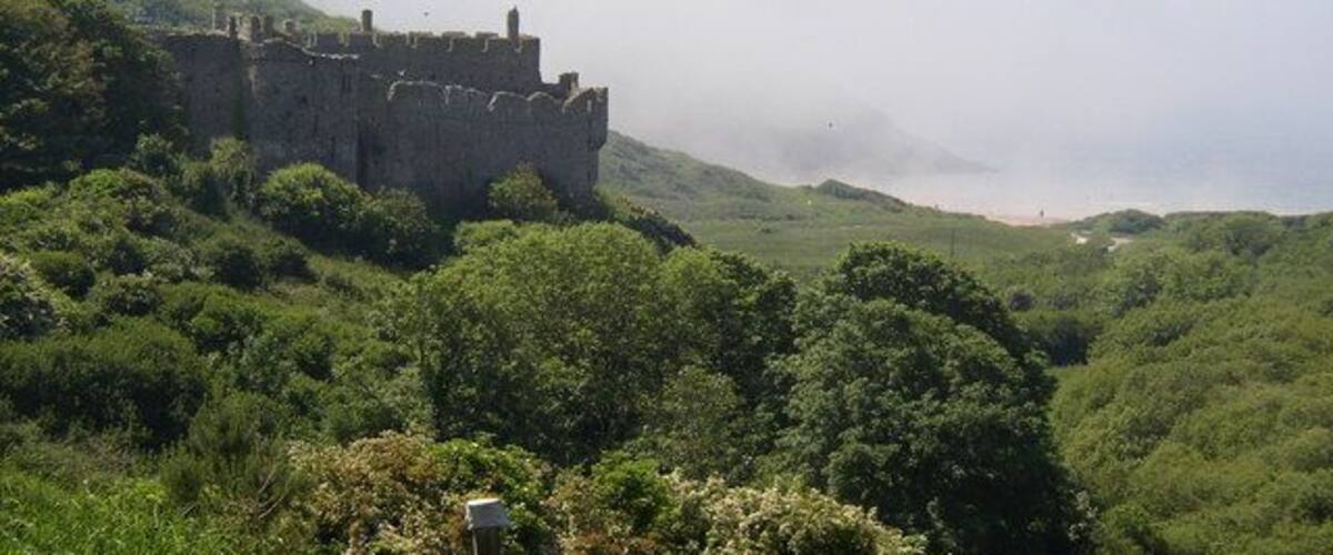 A medieval castle on a hill surrounded by lush greenery.