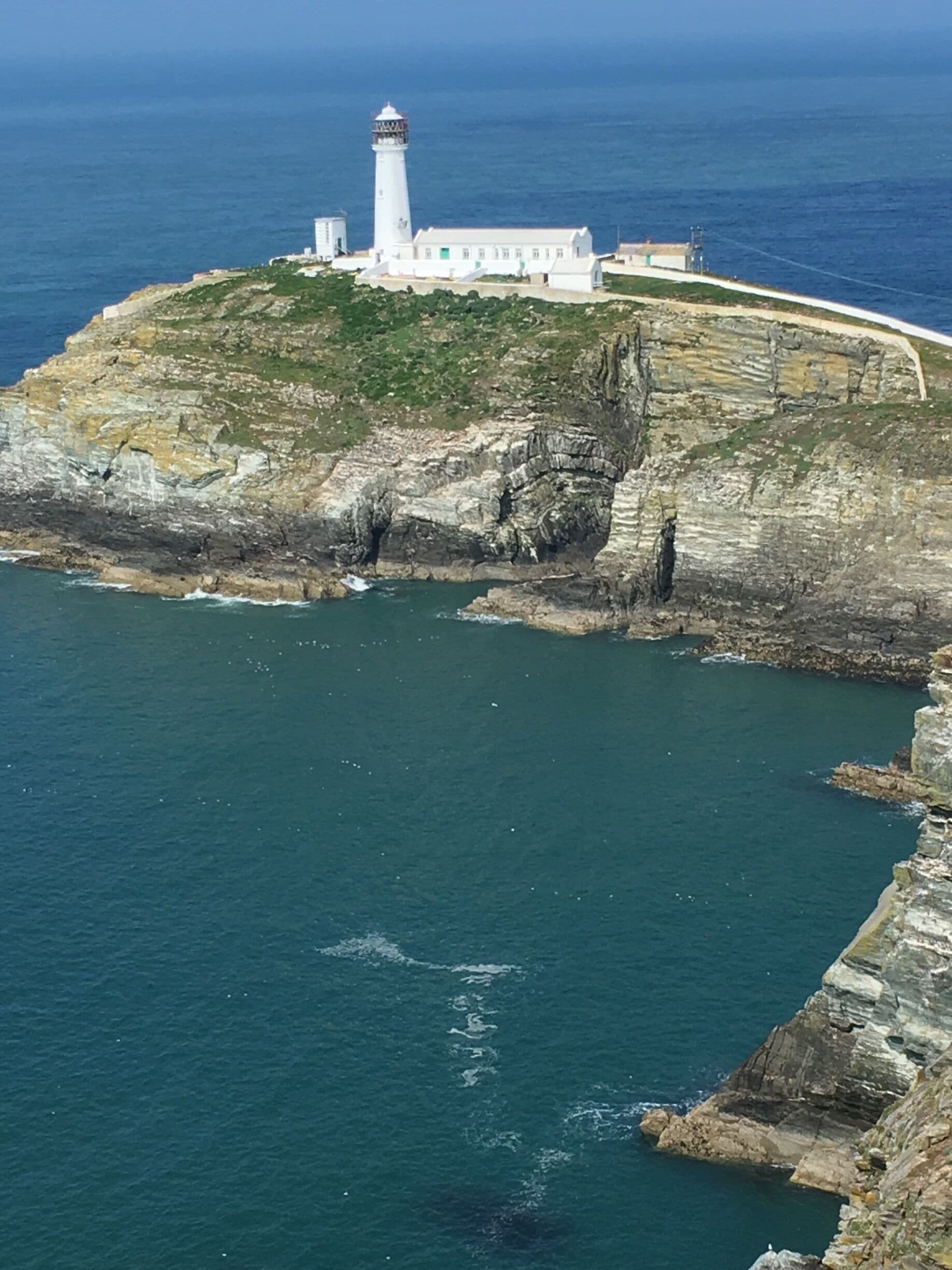 A lighthouse on a rocky cliff by the sea.