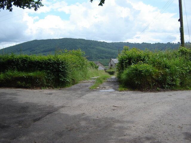Un camino rural que lleva a una casa, con una colina al fondo.