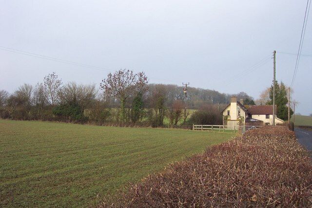 A rural landscape with a field, a small house, and a fence.
