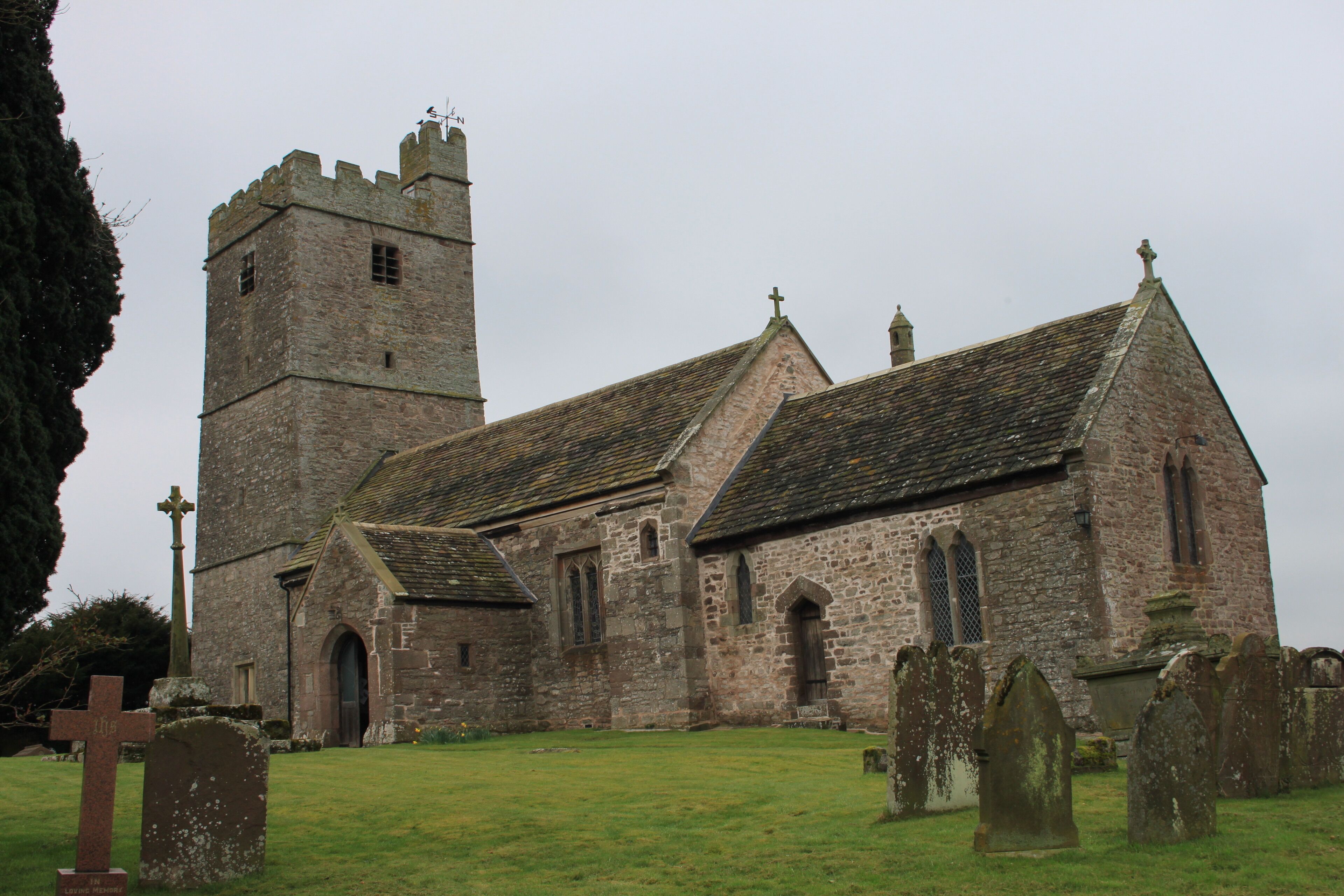 A historic church with a tall tower and a graveyard.