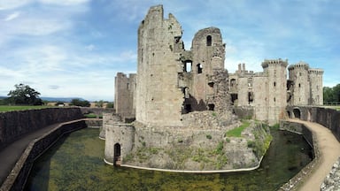 A historic castle with ruins, a moat, and a clear sky.