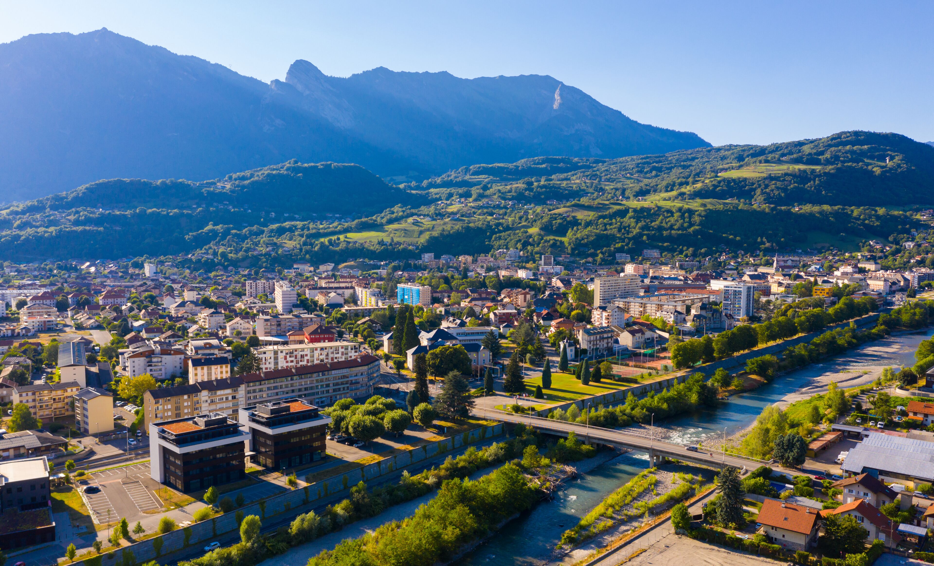 A cityscape with a river, buildings, and mountains in the background.