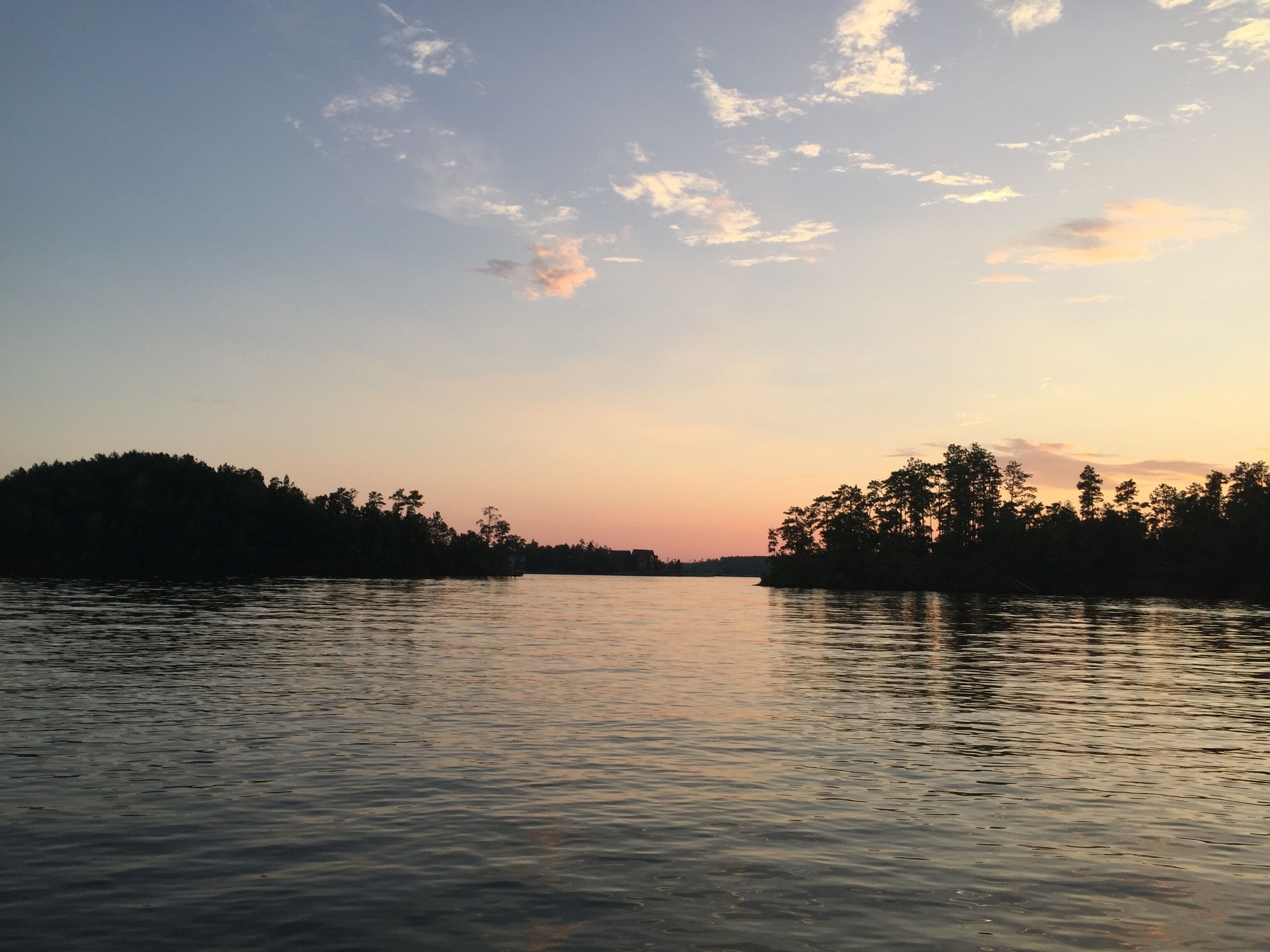 Un lago tranquilo al atardecer con siluetas de árboles en la orilla.