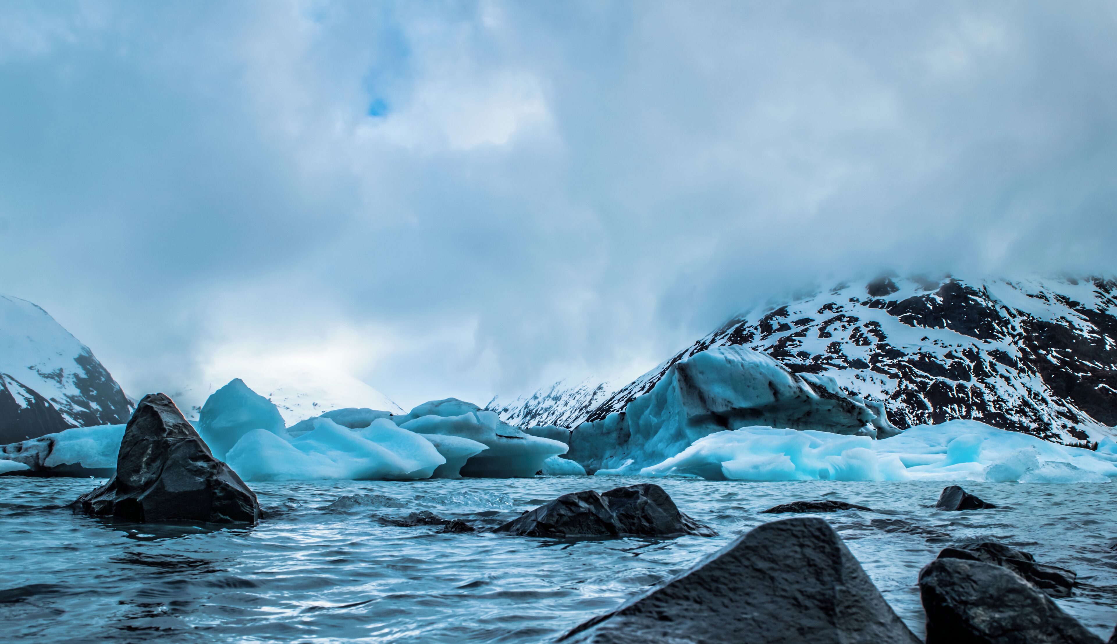 A glacier with icebergs and mountains in the background.