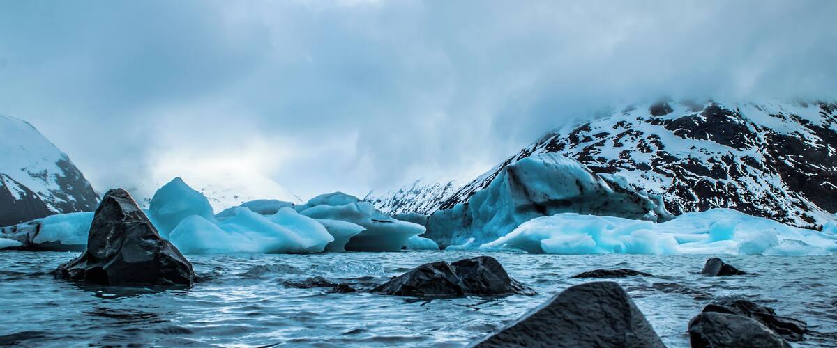 A glacier with icebergs and mountains in the background.
