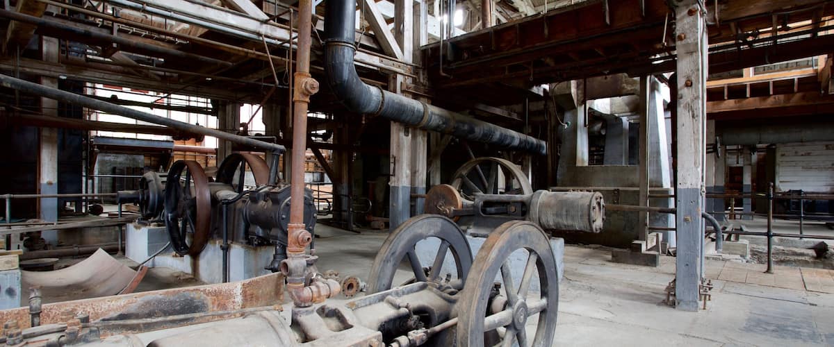 An industrial setting with large machinery, pipes, and wheels.