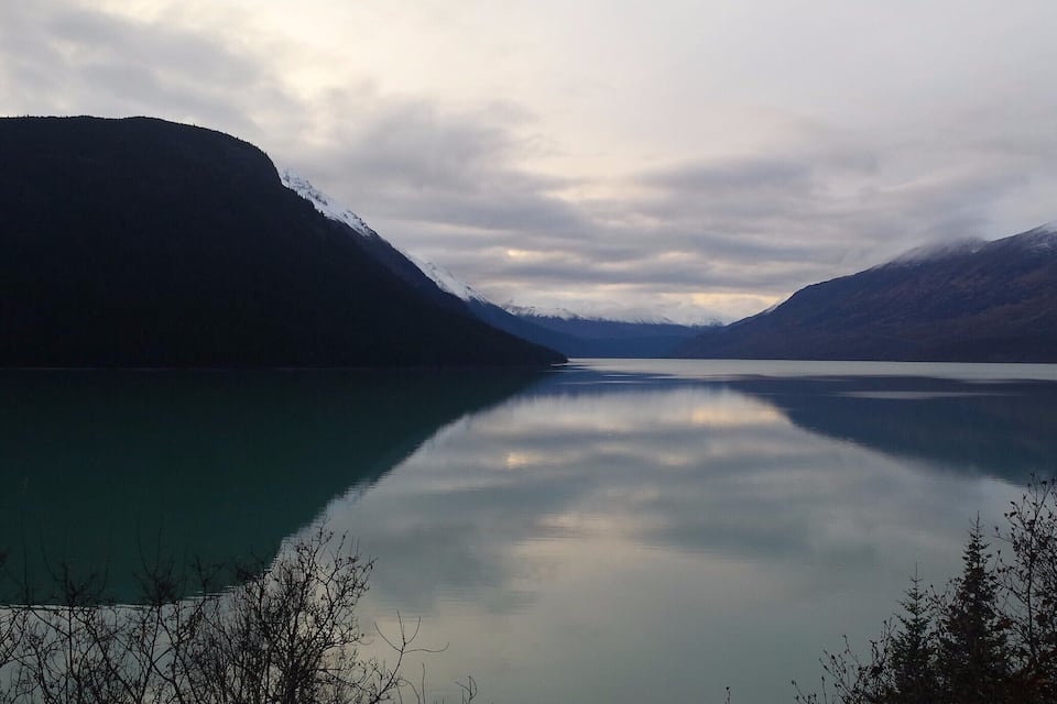Un lago tranquilo rodeado de montañas con picos nevados.