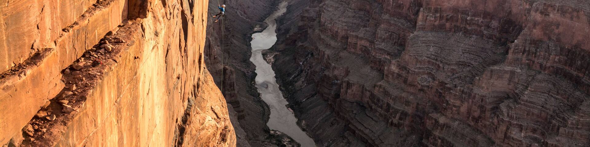 A canyon with layered rock formations and a river running through it.