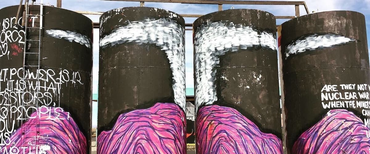Four large cylindrical tanks with graffiti and painted surfaces.
