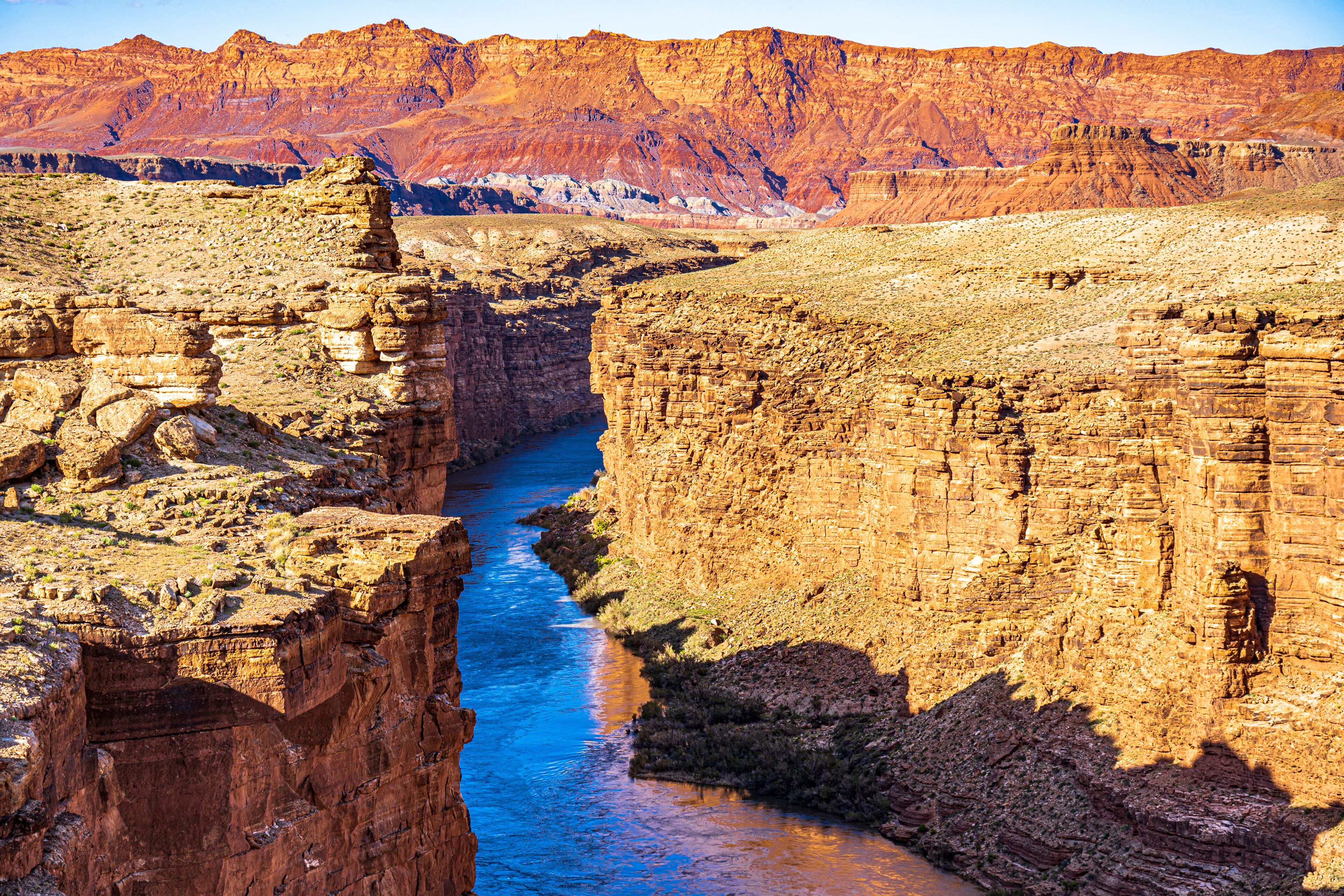 A canyon with a river, layered rock formations, and distant mountains.