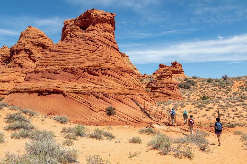A desert landscape with red rock formations and hikers.