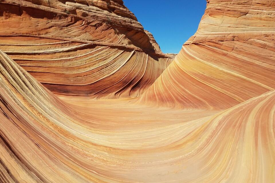 A canyon with layered rock formations and a clear blue sky.