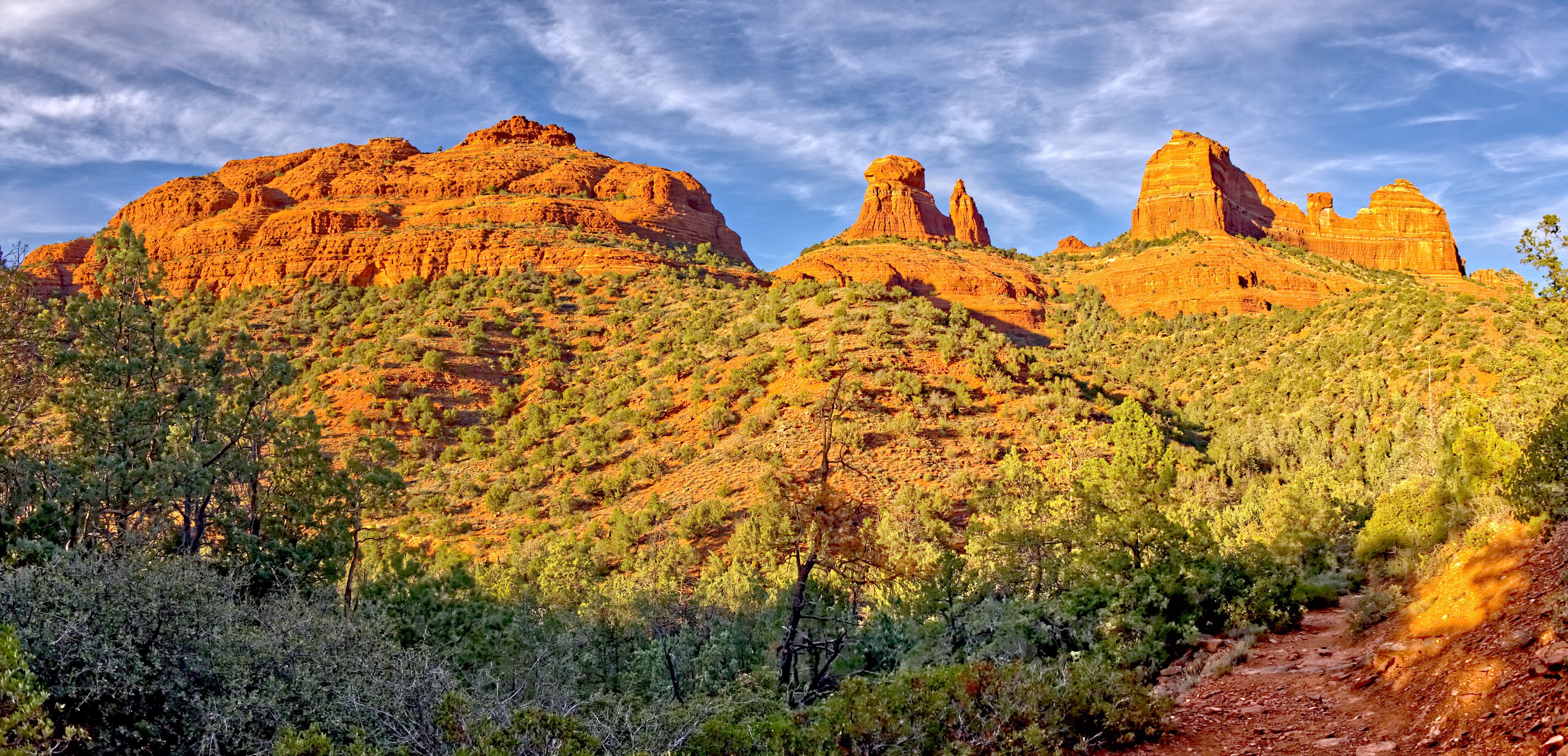 A desert landscape with red rock formations and sparse vegetation.
