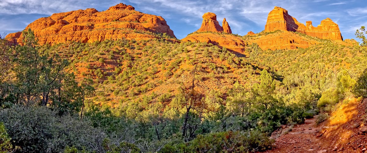 A desert landscape with red rock formations and sparse vegetation.