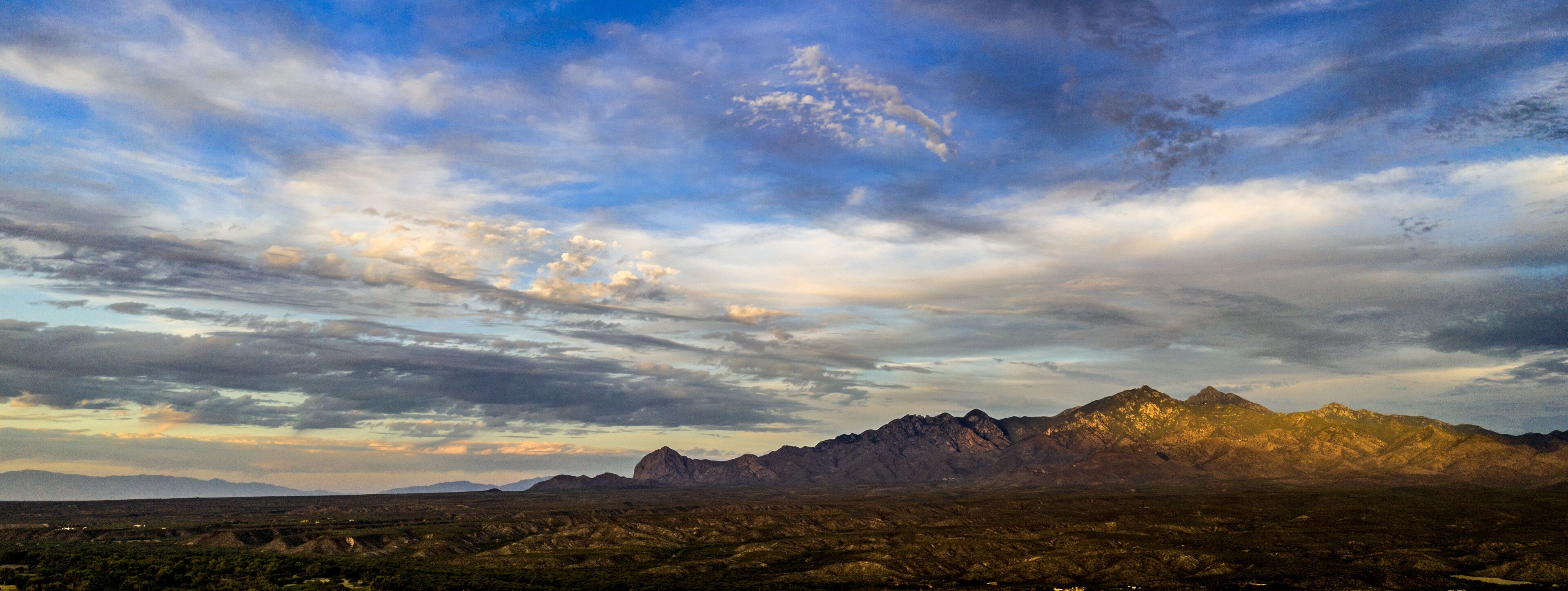 A mountainous landscape with a clear sky and scattered clouds.