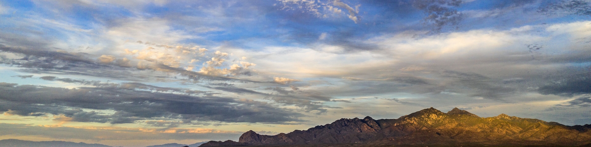 A mountainous landscape with a clear sky and scattered clouds.