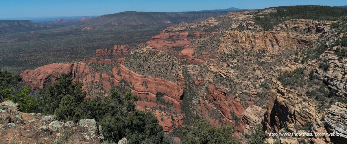 A canyon with red rock formations and sparse vegetation.