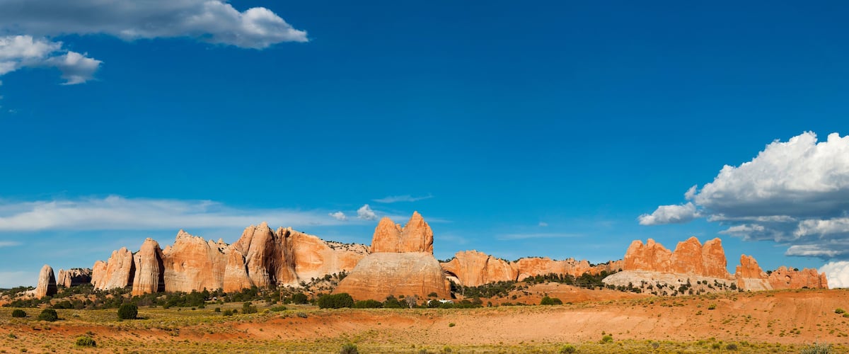 A desert landscape with prominent rock formations and a clear blue sky.