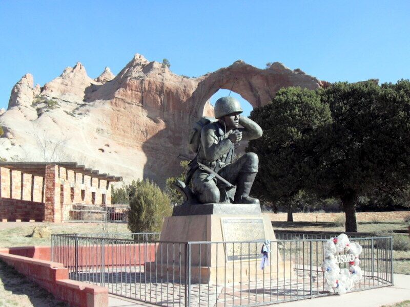 Window Rock is a small city that serves as the seat of governmental capital of the Navajo Nation, the largest territory of a Sovereign Native American Nation in North America. It lies adjacent to the Arizona and New Mexico state lines.
This photo was taken in WINDOW ROCK NAVAJO TRIBAL PARK & VETERAN'S MEMORIAL, this park near the Navajo Nation Administration Center features the graceful Redstone Arch for which the capital is named.
More recently, the Navajo Nation has built a Veterans Memorial at the base of Window Rock to honor the many Navajos who served in the U. S. military.  Many Navajo soldiers are recognized in the annals of history for their role as Code Talkers, whereby they used the Navajo language to create a code that was never broken by the enemy.  Historians credit the Navajo Code Talkers for helping to win World War II.
