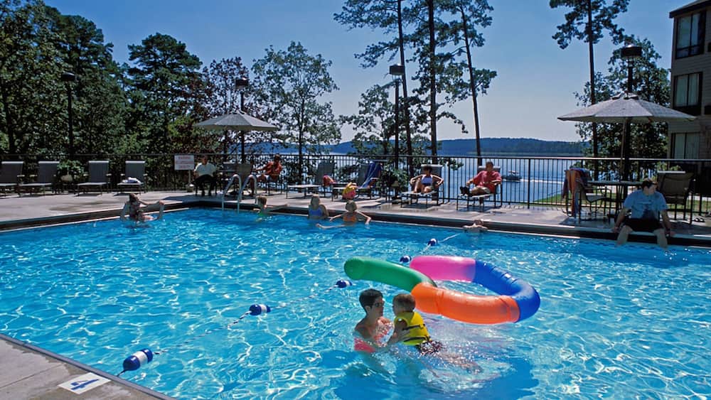 A swimming pool with people and inflatable rings.