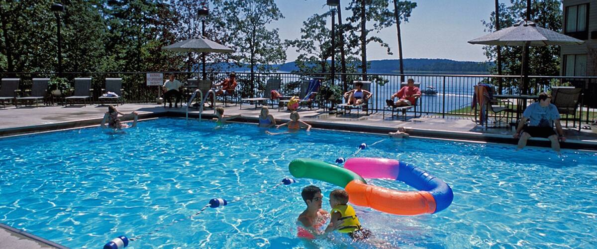 A swimming pool with people and inflatable rings.