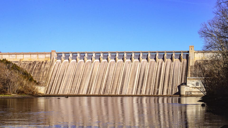 A large dam with water flowing over its spillway.