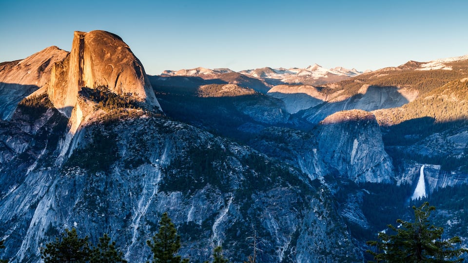 A mountain landscape with a prominent rock formation and a waterfall.