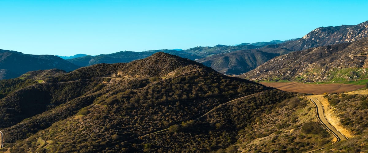 A mountainous landscape with winding roads and green valleys.