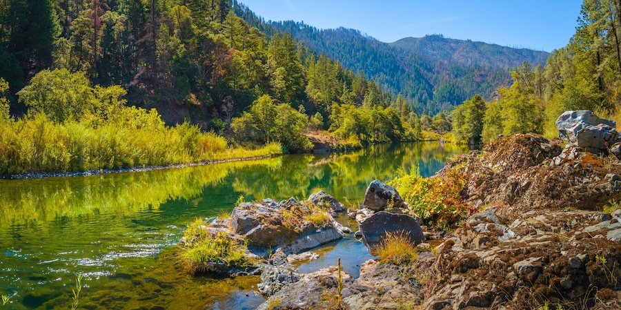 Autumn foliage and tranquil water reflections over the rocky creek on Trinity River near Del Loma, Northern California