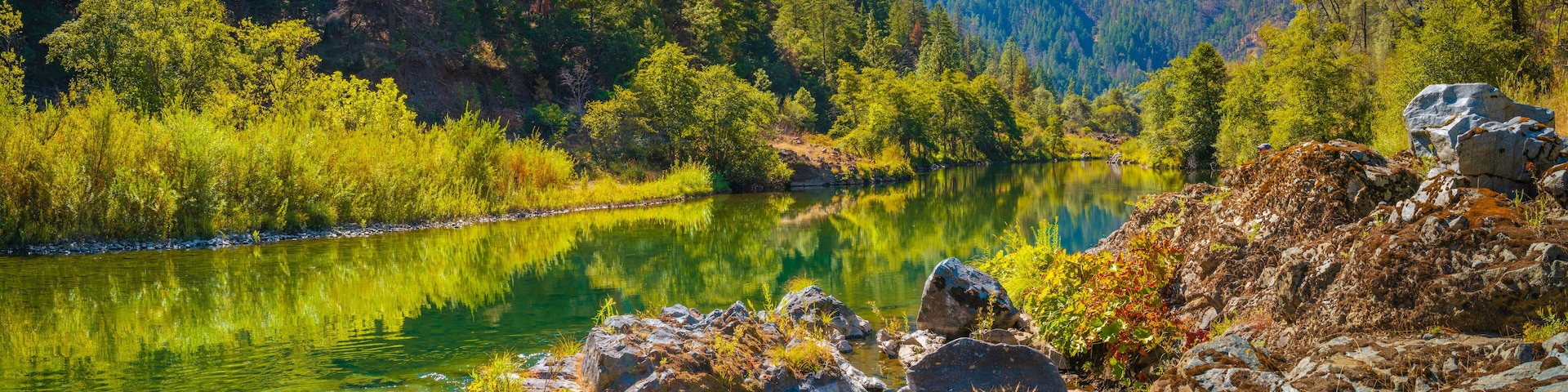 Autumn foliage and tranquil water reflections over the rocky creek on Trinity River near Del Loma, Northern California