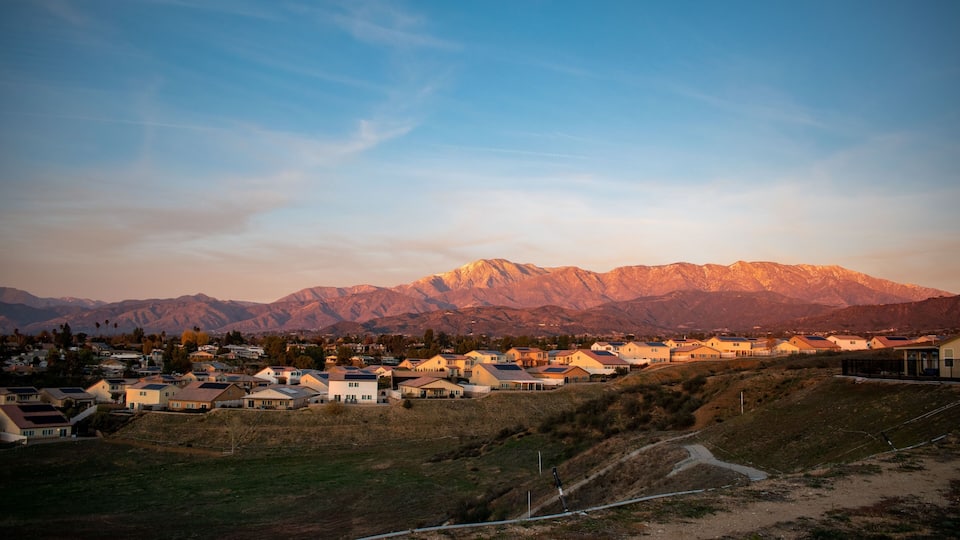 A residential area with houses and a mountain range in the background.