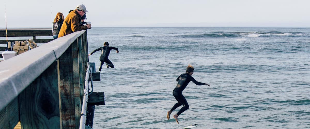 Surfers jumping off the pier.