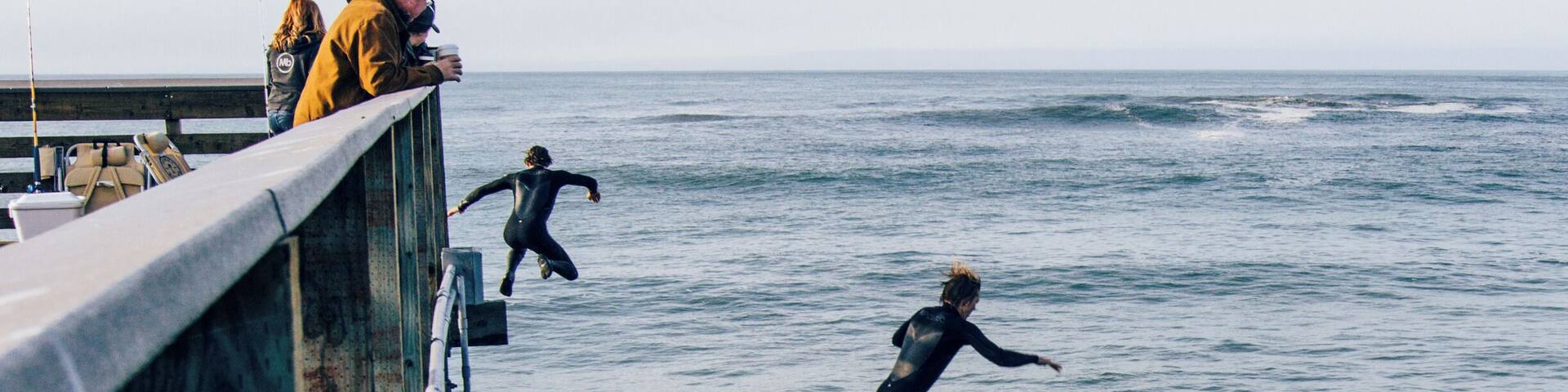 Surfers jumping off the pier.