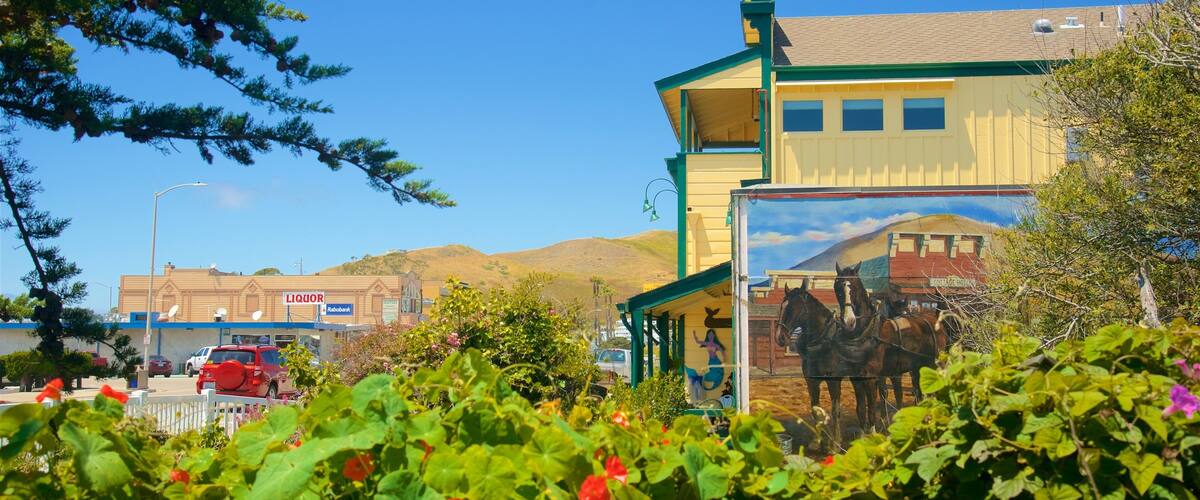 A building with a mural of horses, surrounded by greenery and a clear blue sky.