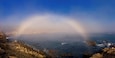 A coastal landscape with a sea spray arch over the ocean.